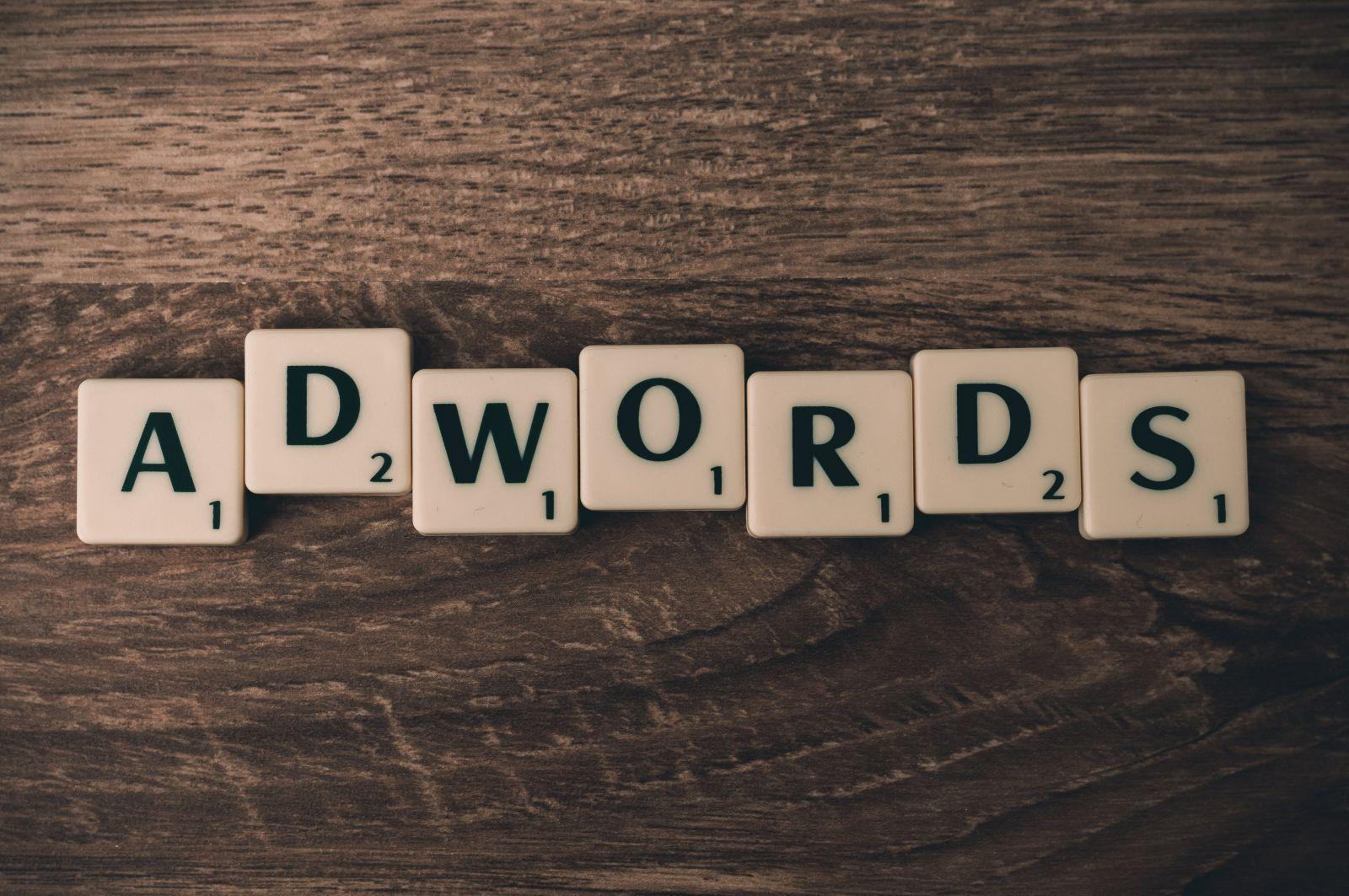 Scrabble letter tiles spelling the word AdWords on a wooden surface