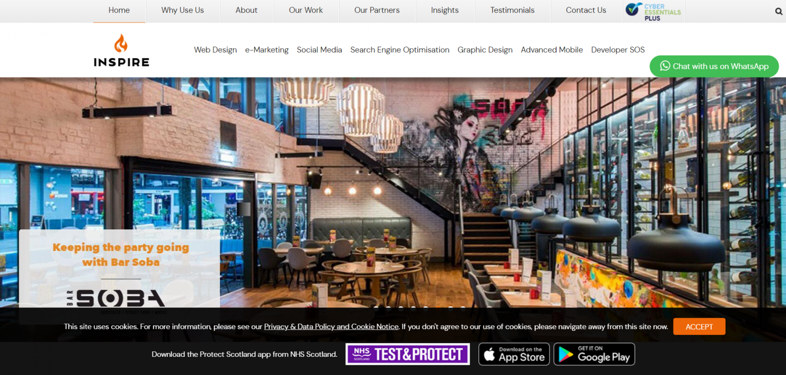 Interior view of Bar Soba restaurant showing modern dining area with tables and chairs, artistic mural on brick wall, wine display, and hanging lights