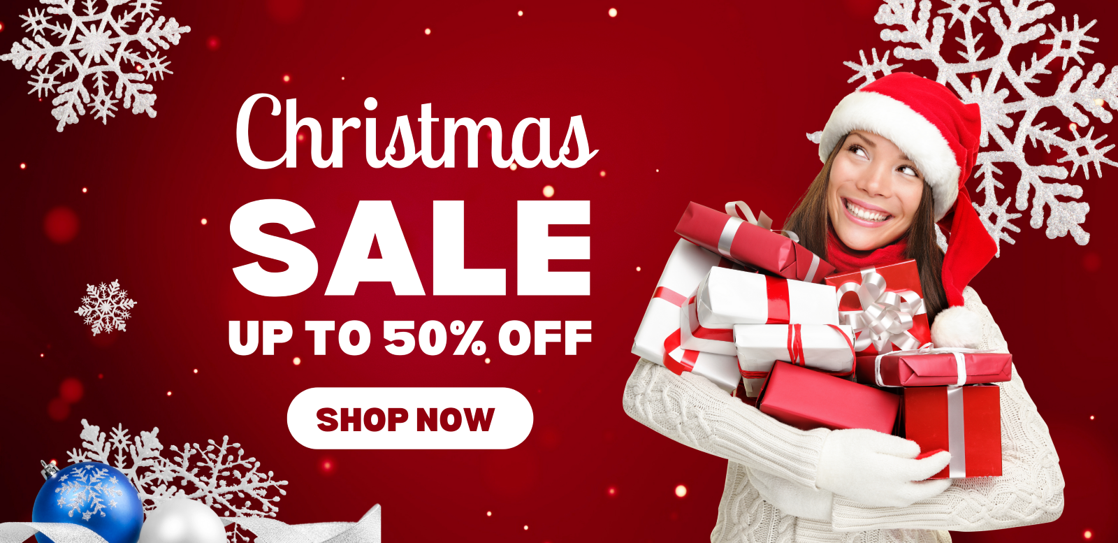 Smiling woman wearing a Santa hat and gloves holding a stack of red and white wrapped Christmas presents on a red background with snowflakes and Christmas baubles
