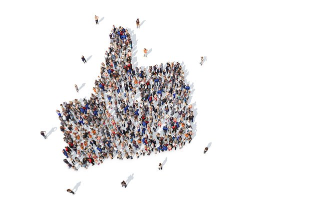 Large group of people forming a thumbs-up symbol viewed from above on white background