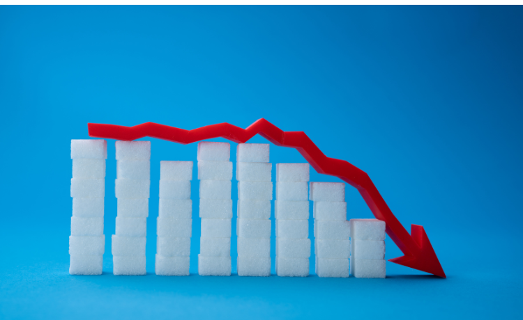 Stacked sugar cubes arranged as a bar graph with a red arrow showing a downward trend