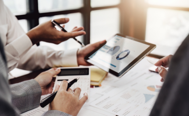 People reviewing financial charts on a tablet and using a calculator to discuss digital marketing budget