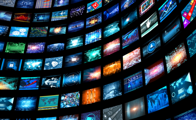 Curved array of digital screens displaying news, data charts, and technological imagery