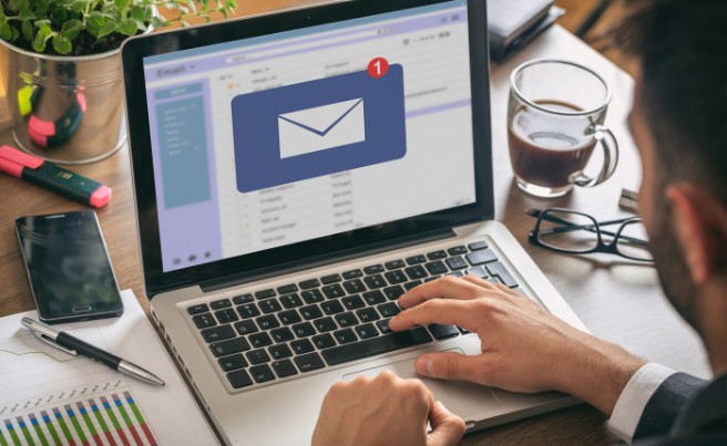 Person using laptop showing an email inbox with a new message notification icon on screen