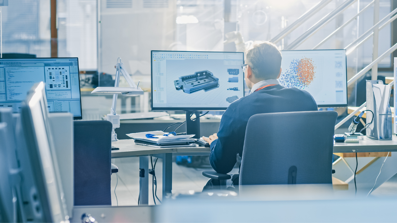 Man working at three computer monitors in an office, viewing 3D CAD design and data graphs