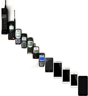 A range of mobile phones arranged from oldest large brick-style models to modern sleek smartphones showing the evolution of mobile phone design