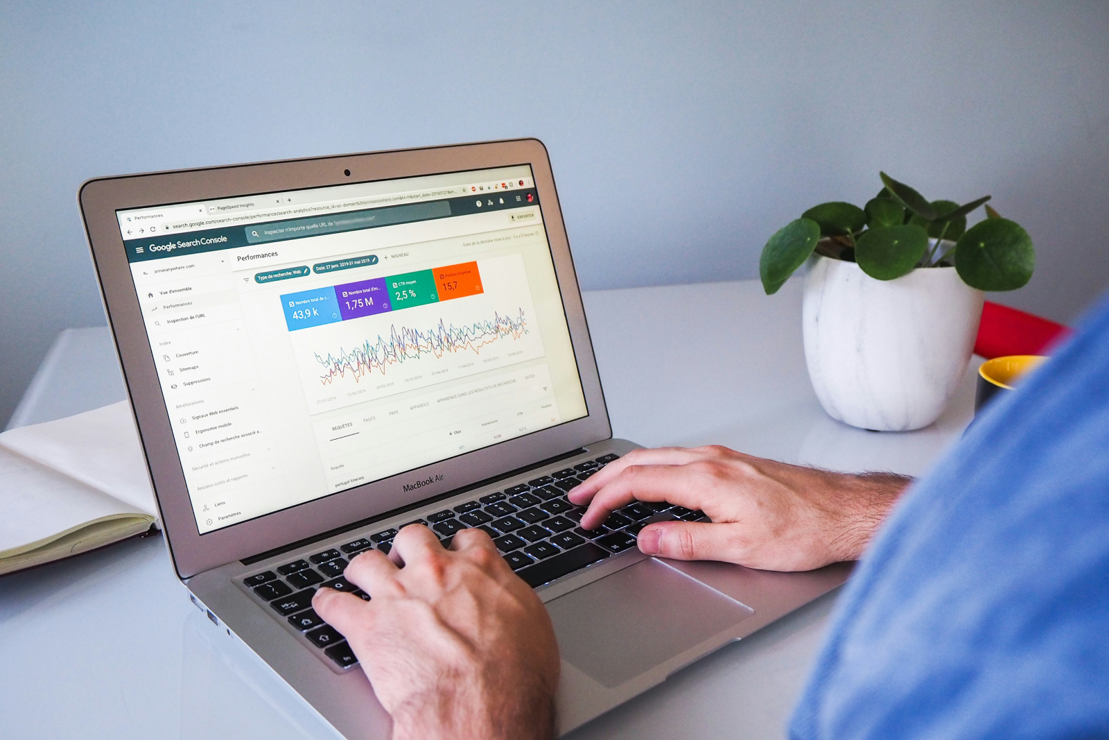 Person working on a MacBook Air showing Google Search Console performance metrics with colourful data graphs and statistics
