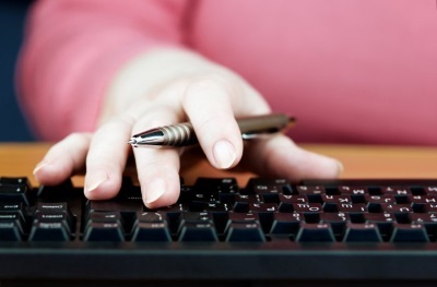 Website Content Optimisation - Inspire IT Services Person holding a pen while typing on a computer keyboard