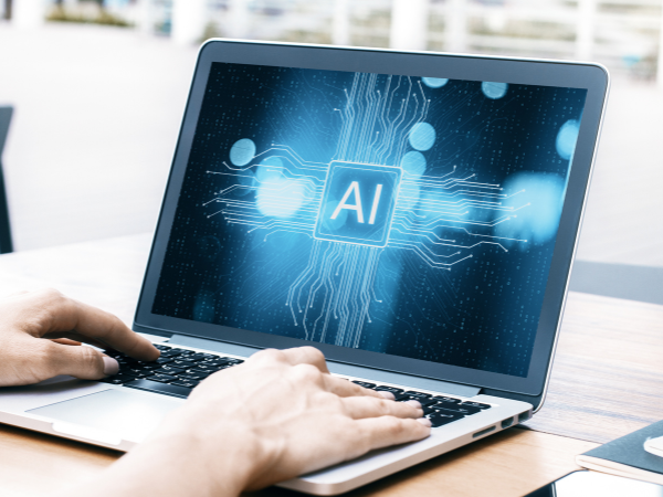 Person using a laptop displaying a glowing AI circuit pattern on the screen representing artificial intelligence technology