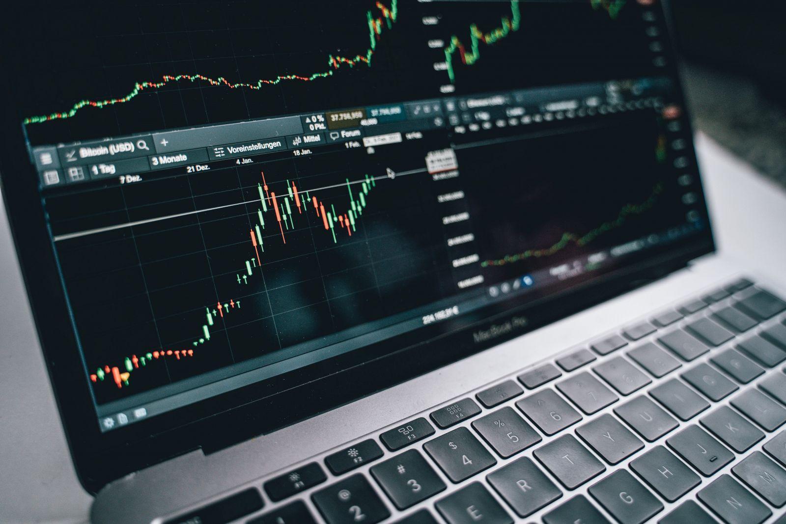 Close-up of a laptop keyboard and screen displaying Bitcoin price charts with candlestick graphs and trend lines