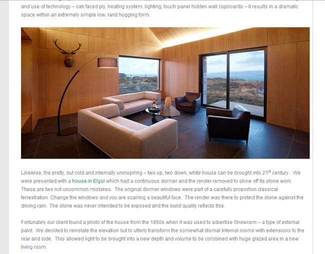 Dualchas Austerity Blog Interior of a modern living room featuring wood panelled walls and ceiling with large windows overlooking a rocky coastal landscape, furnished with a beige sofa, two dark armchairs, black tile flooring, and a standing lamp