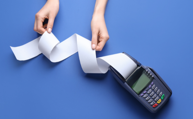 Hands holding a long receipt roll emerging from a payment terminal on a blue background