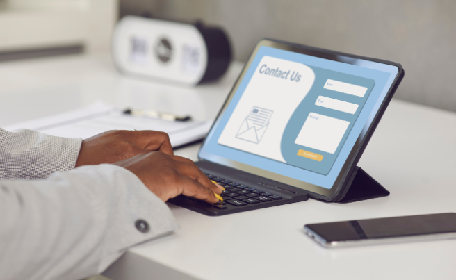 Person typing on a tablet with a contact us form displayed on the screen