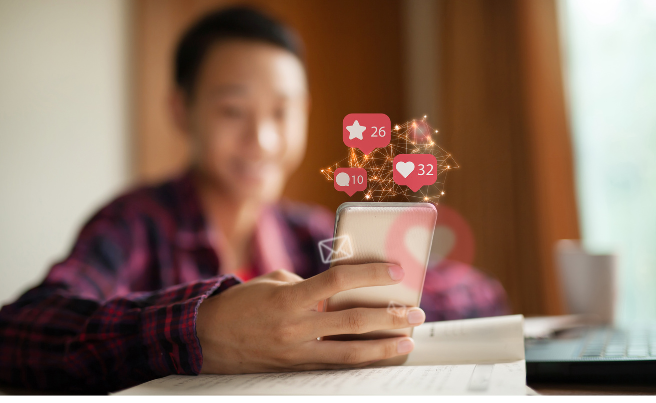 Person holding a smartphone displaying floating social media icons for likes, comments and notifications