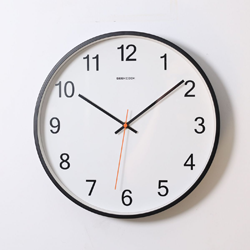 Round wall clock with black frame and white face showing time at approximately 10:10:32