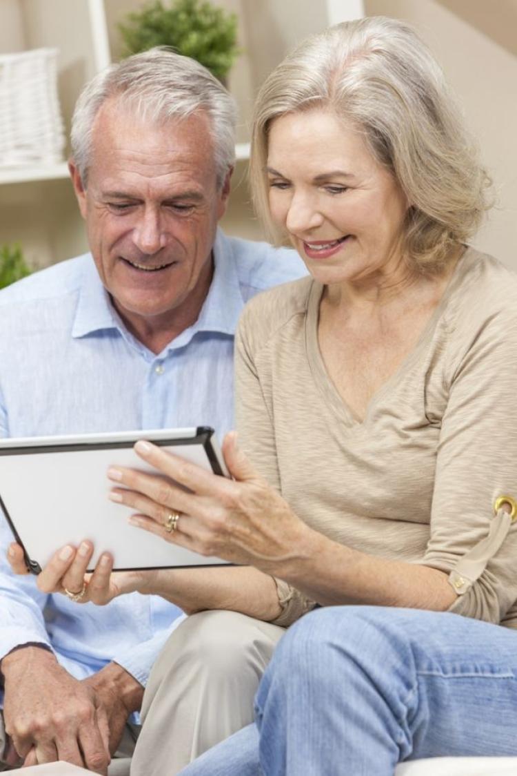 Smiling senior couple sitting and looking at a tablet device together indoors