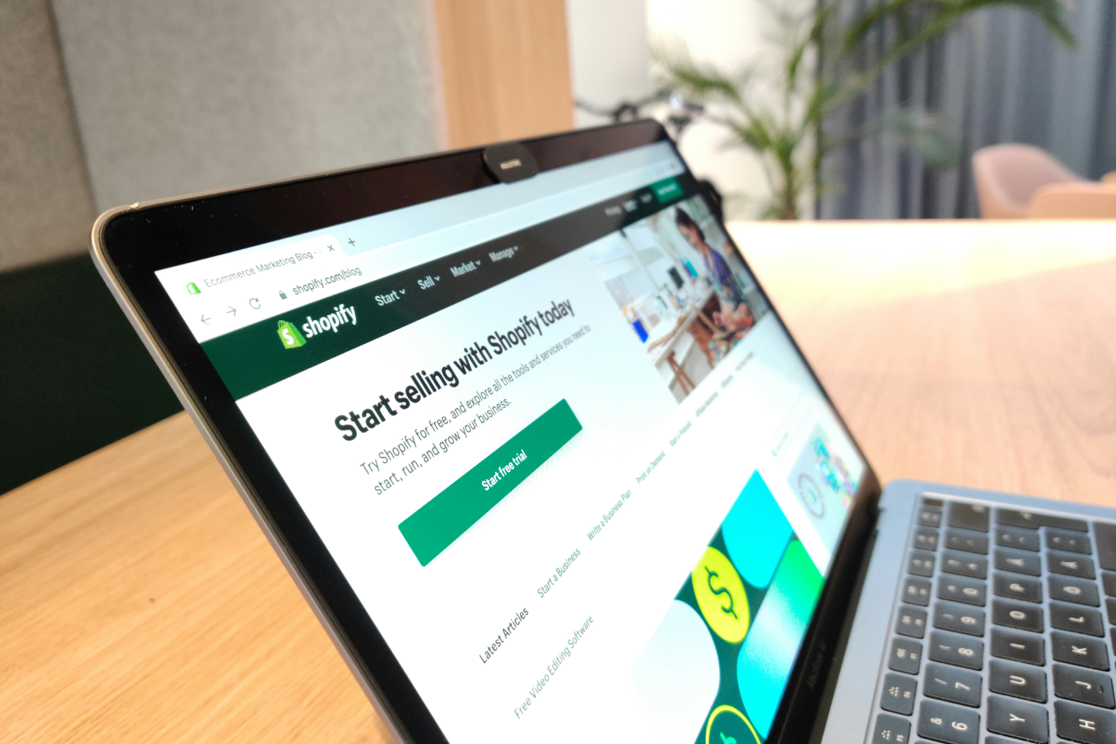 Laptop screen displaying Shopify website with 'Start selling with Shopify today' message and options to explore tools and services