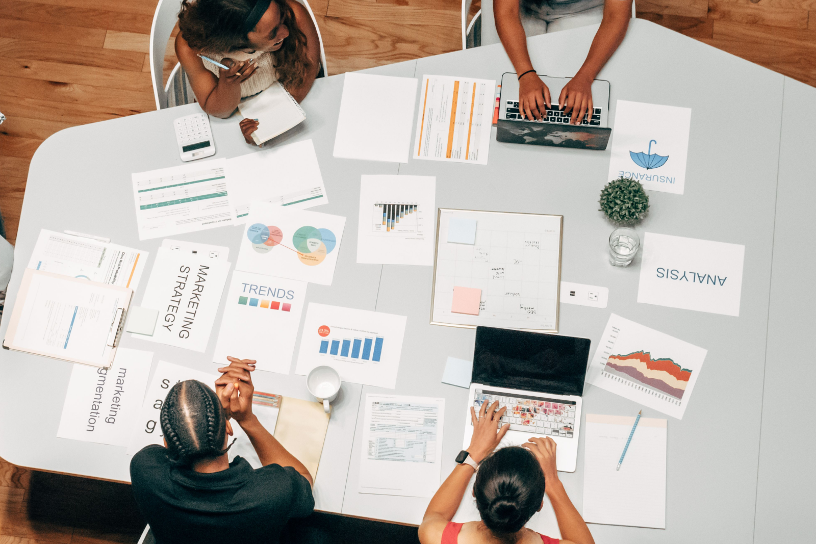 Overhead view of a diverse team discussing marketing strategy with charts, graphs and laptops on a table