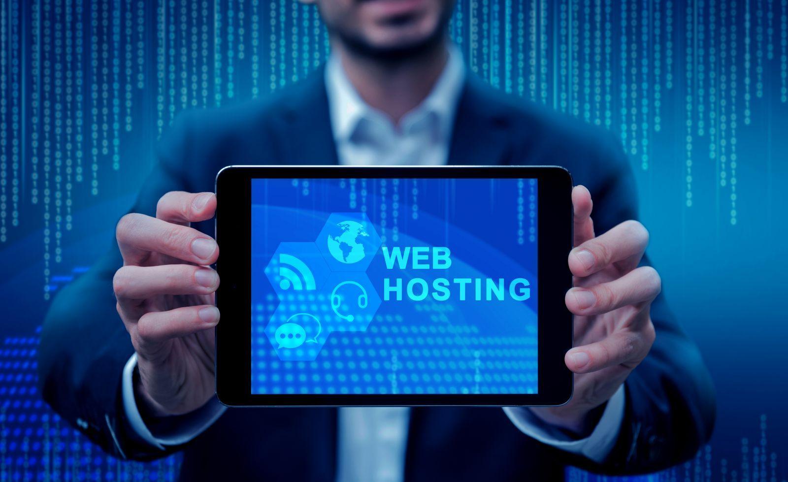 Man in suit holding a tablet displaying a blue screen with the text 'Web Hosting' and digital icons, with a background of blue digital data streams