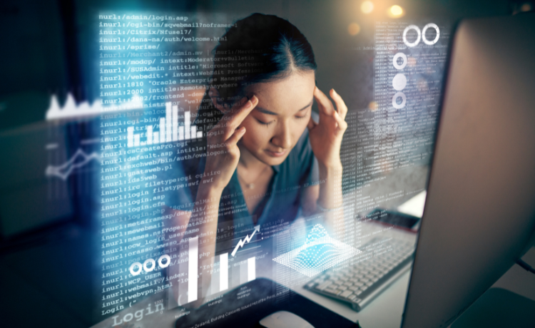 Woman sitting at a desk with hands on her temples surrounded by floating digital data and graphs illustrating information overload and digital stress