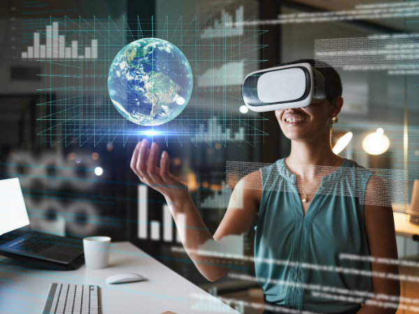 Woman wearing a virtual reality headset interacting with a holographic 3D globe and digital data visuals in a modern office environment