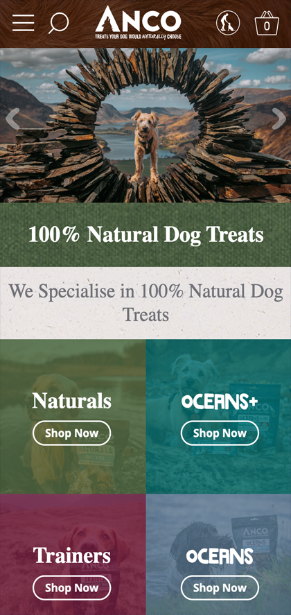 Mobile view of Anco Dog Treats homepage showing a dog framed by a circular stone structure in a mountainous landscape with text highlighting 100% natural dog treats and shopping categories