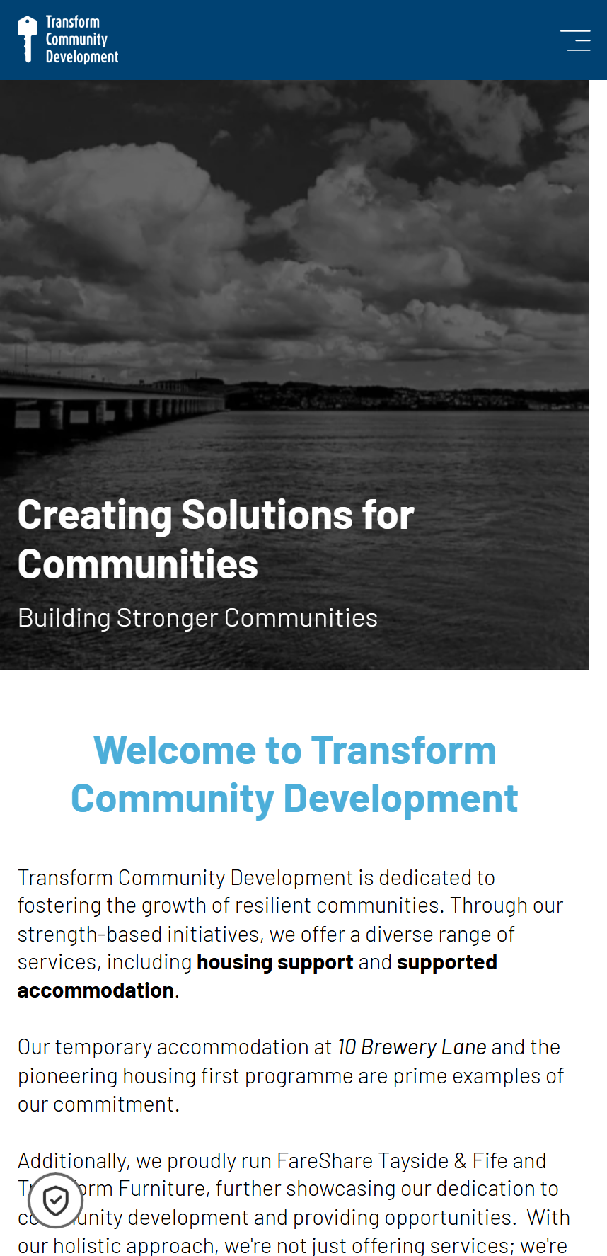 Transform Community Development website homepage on mobile, showing logo, navigation menu, and text about creating solutions for communities with housing support and accommodation services