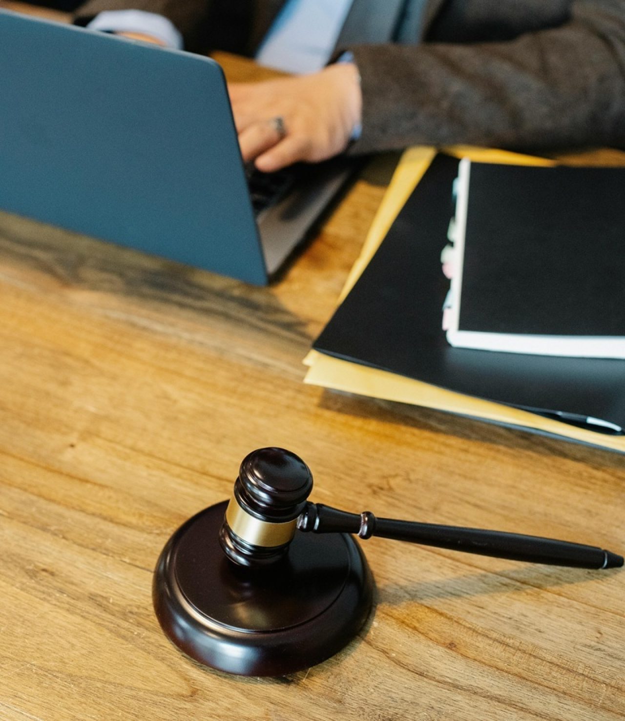 Wooden desk with a judge's gavel, laptop, and documents, indicating a legal expert witness workspace for digital dispute analysis.