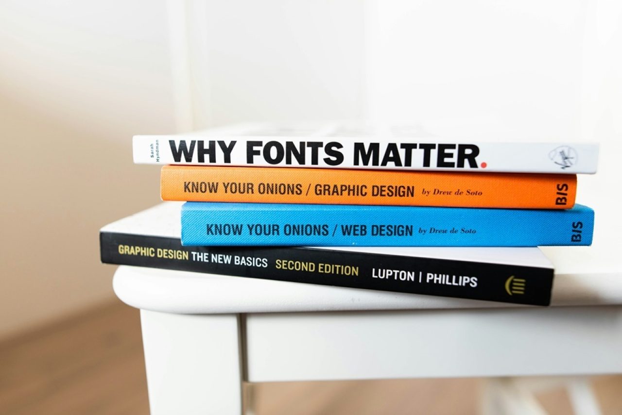 Stack of graphic design and web design books on a table.