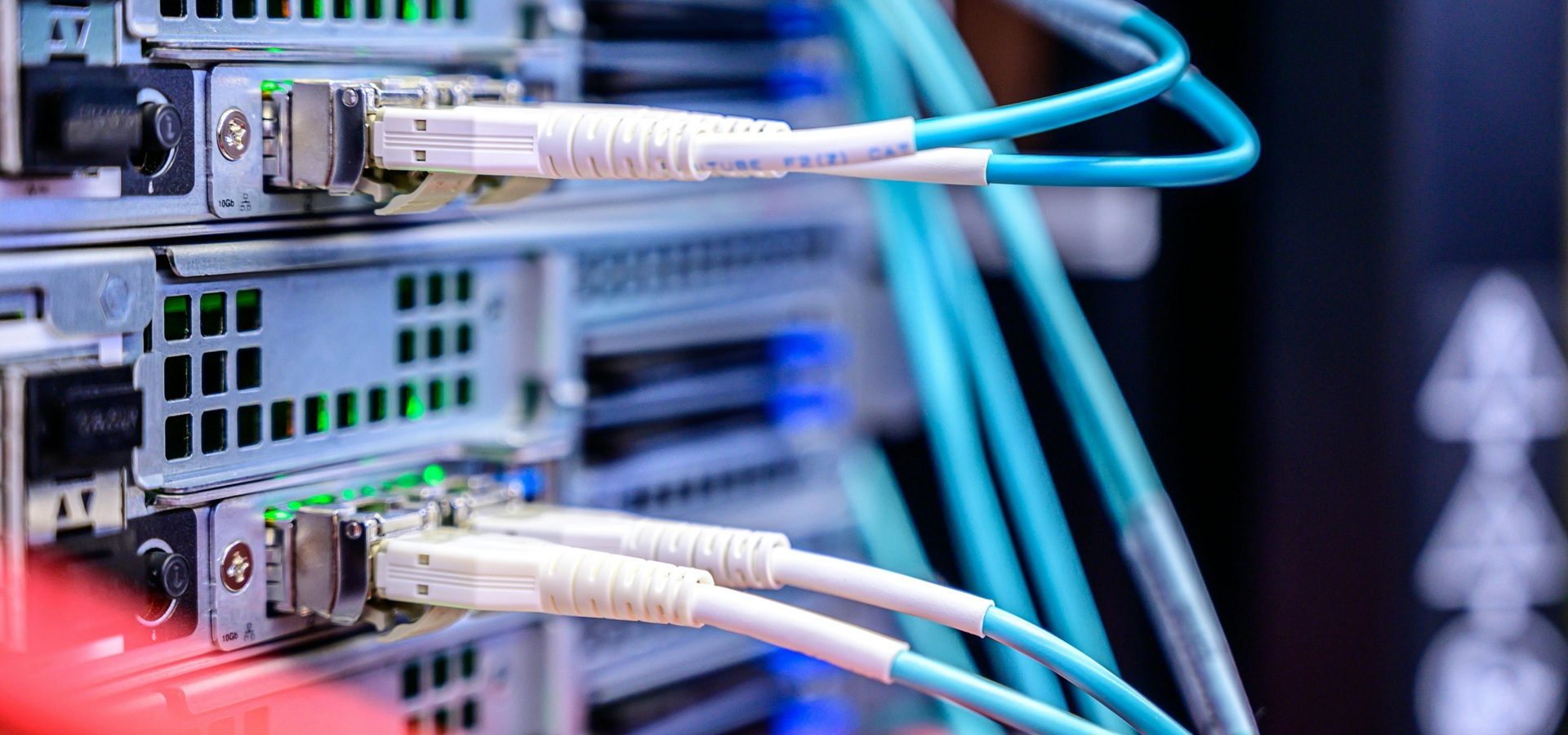 Close-up of network server equipment with connected fibre optic cables showing active status lights