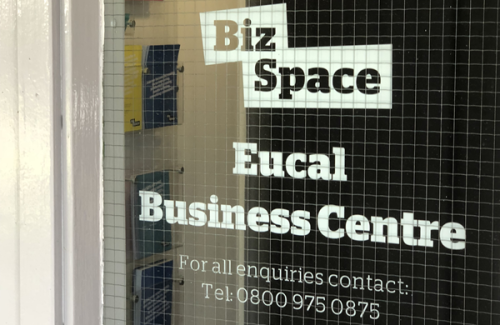 Door window showing sign for Biz Space Eucal Business Centre with contact telephone number