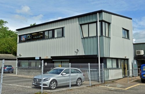 Exterior view of the two-storey Inspire Digital office building in Perth with parked cars and a metal fence