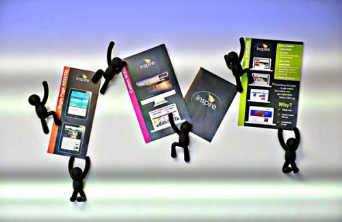 Black office coat hanger figures holding marketing material cards branded with Inspire Digital