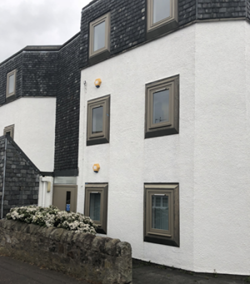 Exterior view of a white and dark grey Edinburgh office building with multiple windows and a small stone wall in front
