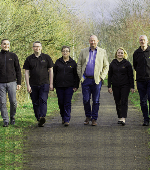 Group of six Inspire staff members walking outdoors on a path with trees and greenery in the background