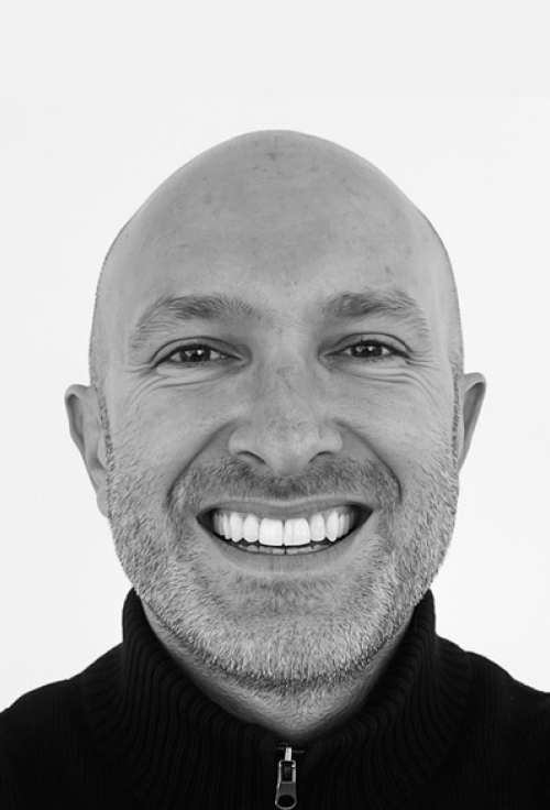 Black-and-white headshot portrait of Chirs Ghilchrist smiling.