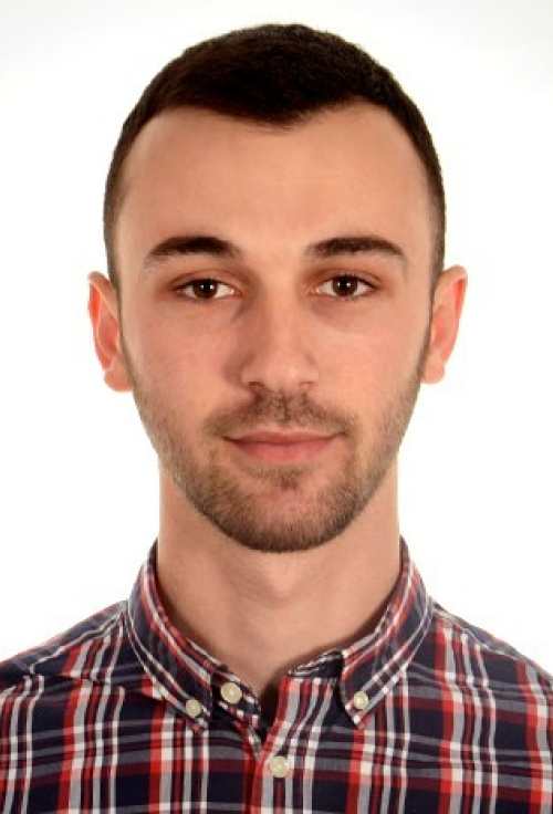 Portrait of a man wearing a red and blue checkered shirt against a plain white background