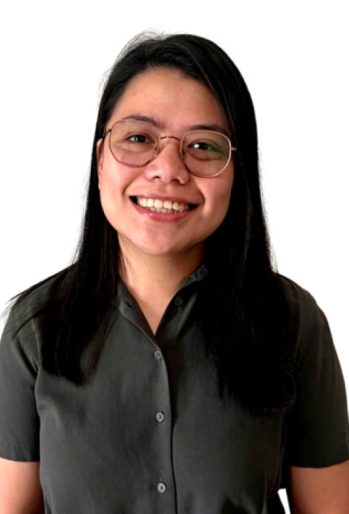 Smiling woman with long dark hair, wearing glasses and a dark short-sleeved shirt against a white background