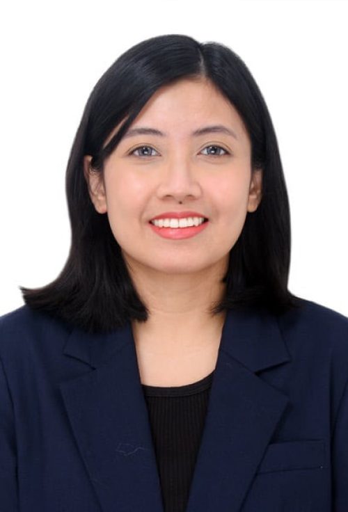 Head and shoulders portrait of a woman with straight dark hair wearing a navy blazer and black top, smiling against a plain white background