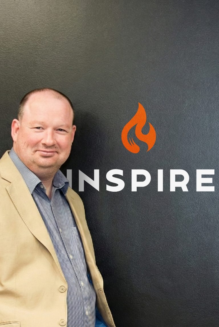 Man standing in front of a black wall with the Inspire logo and text
