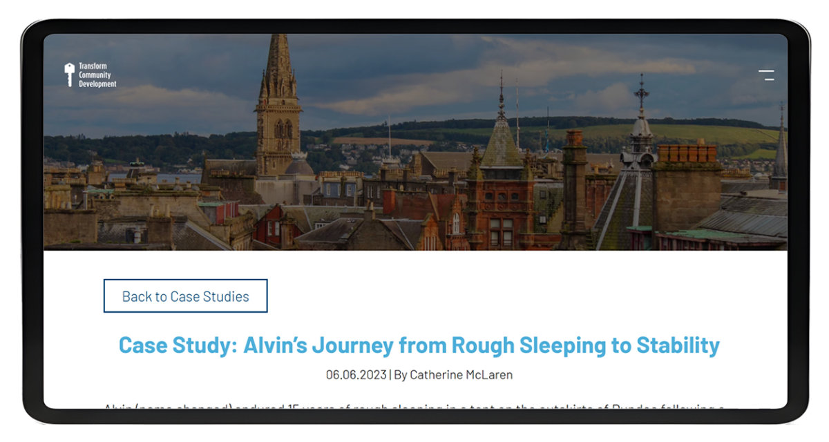 Tablet displaying the homepage of Transform Community Development website featuring a cityscape background and the organisation's logo