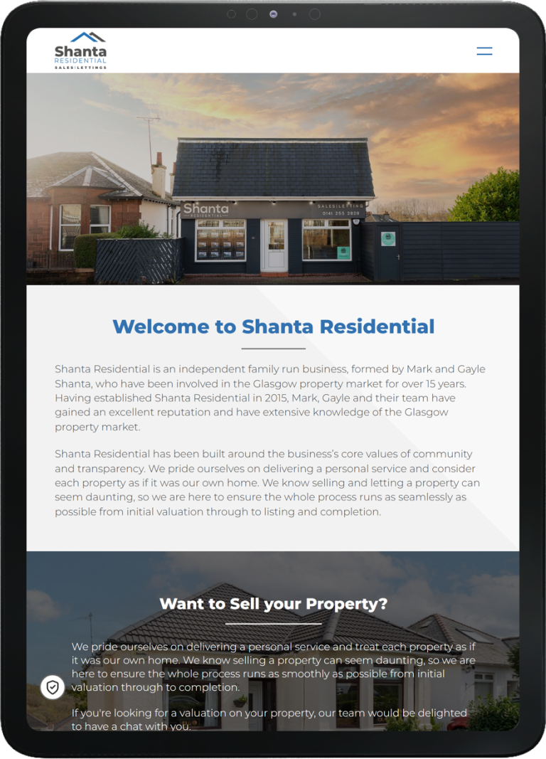 Tablet showing Shanta Residential website homepage with office building exterior under a sunset sky